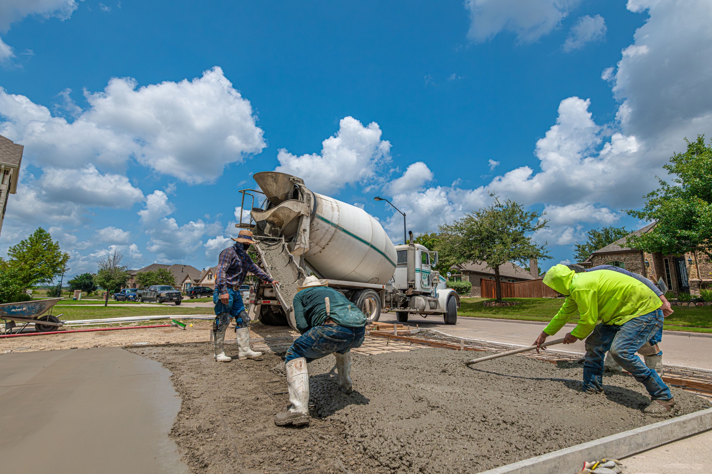 Concrete crew pouring a residential driveway with a mixer truck