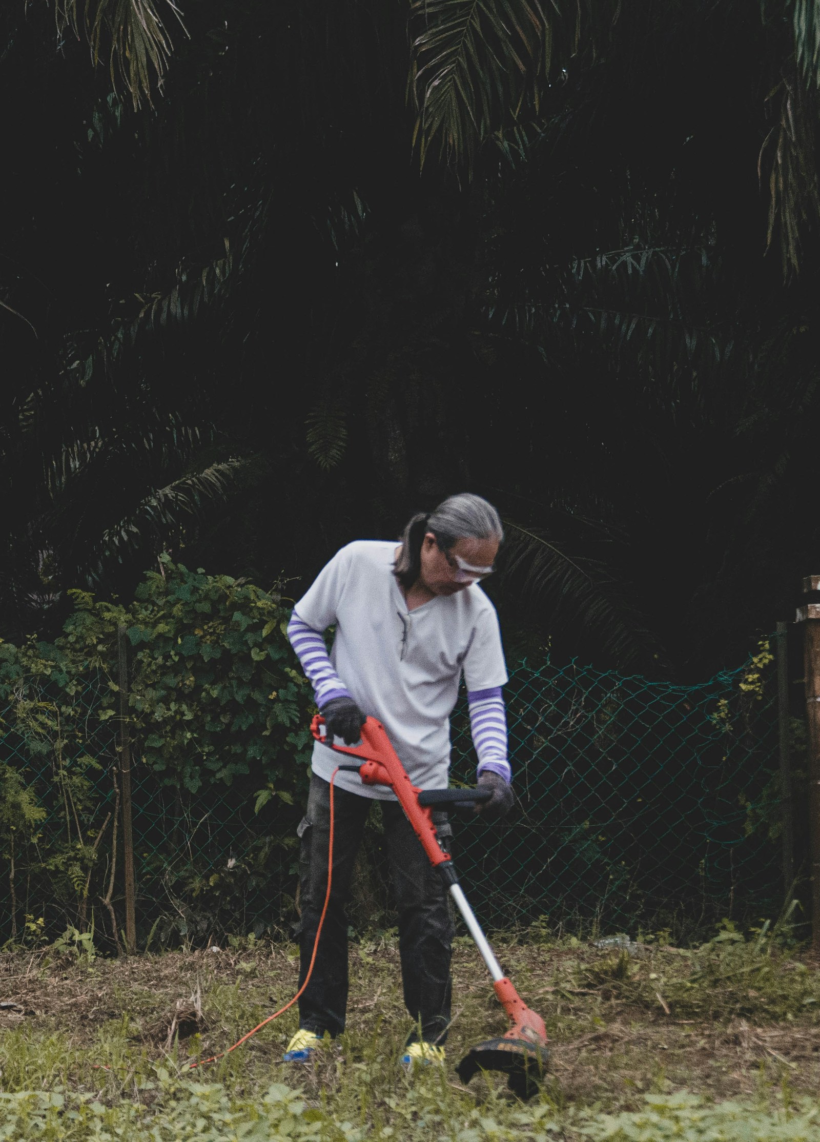 A lawn care worker with a mower, checking his phone