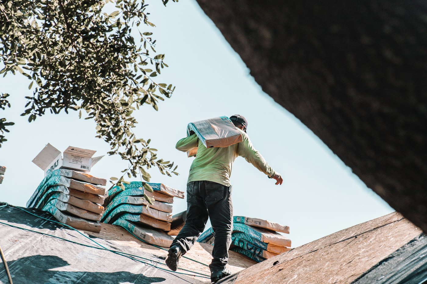 A roofer on a residential roof looking at his phone